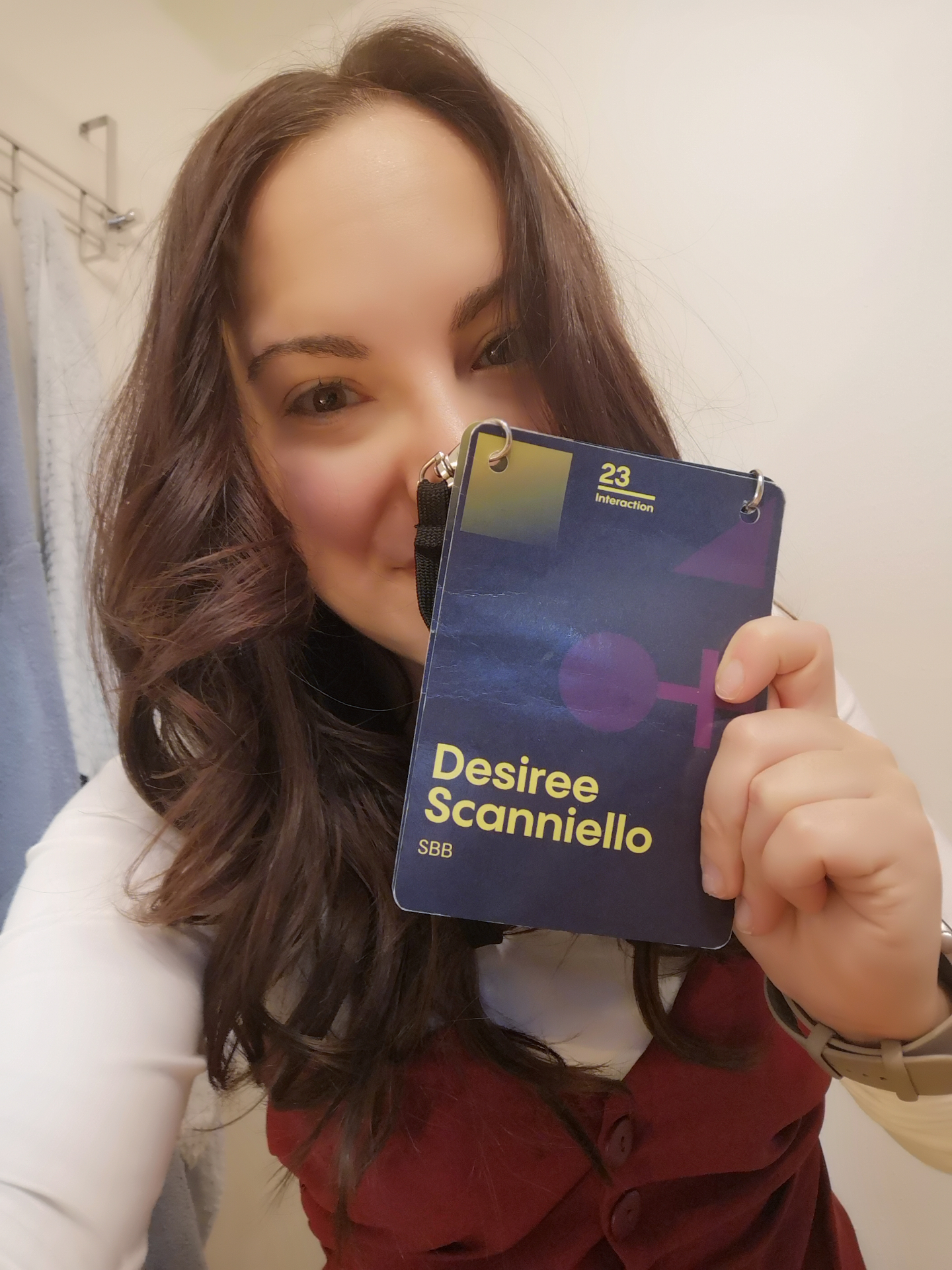 Désirée holding her Interaction 23 volunteer badge, representing SBB.