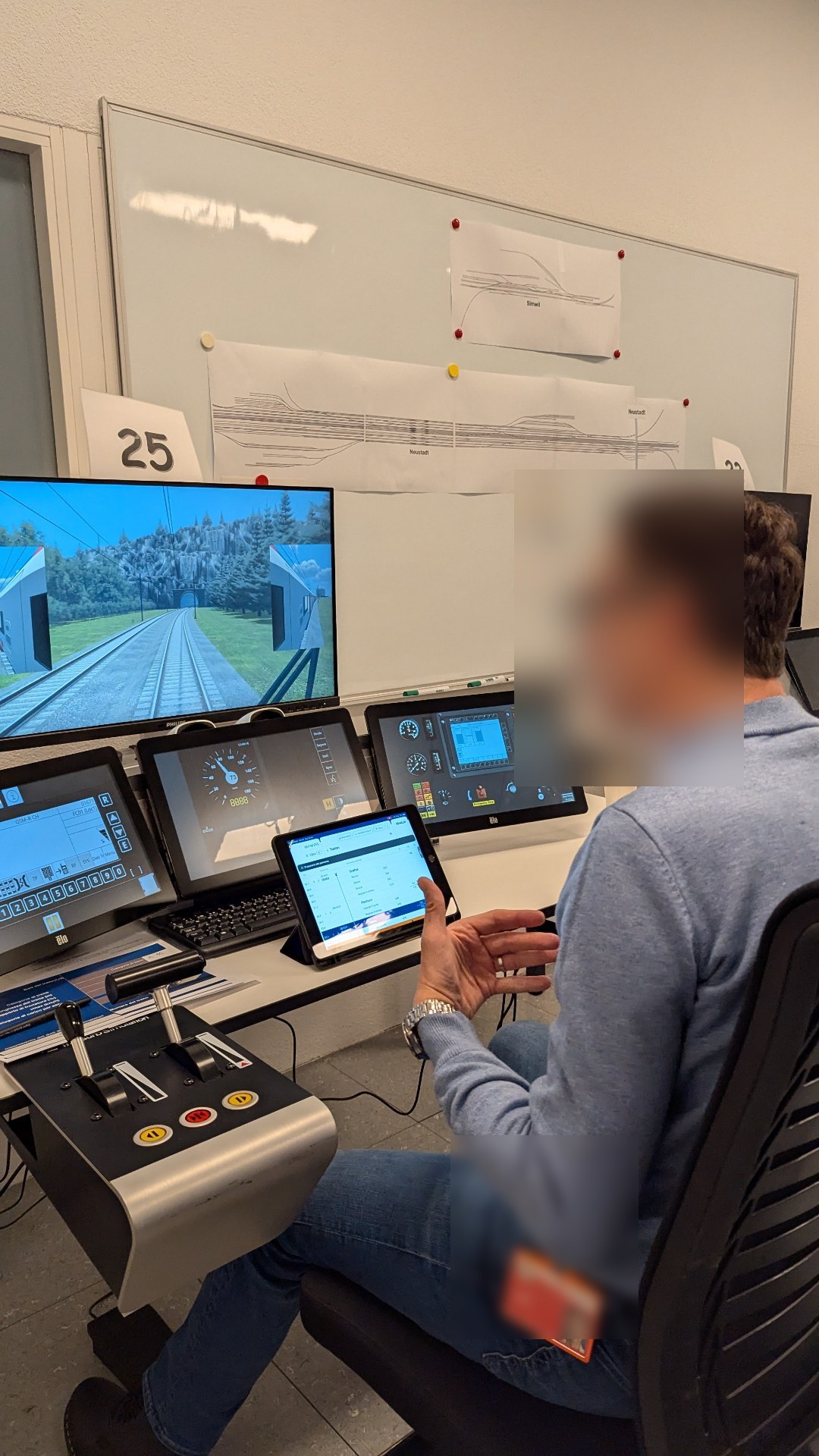 Driver at a high-end training simulator with multiple screens and the DAS iPad in front.