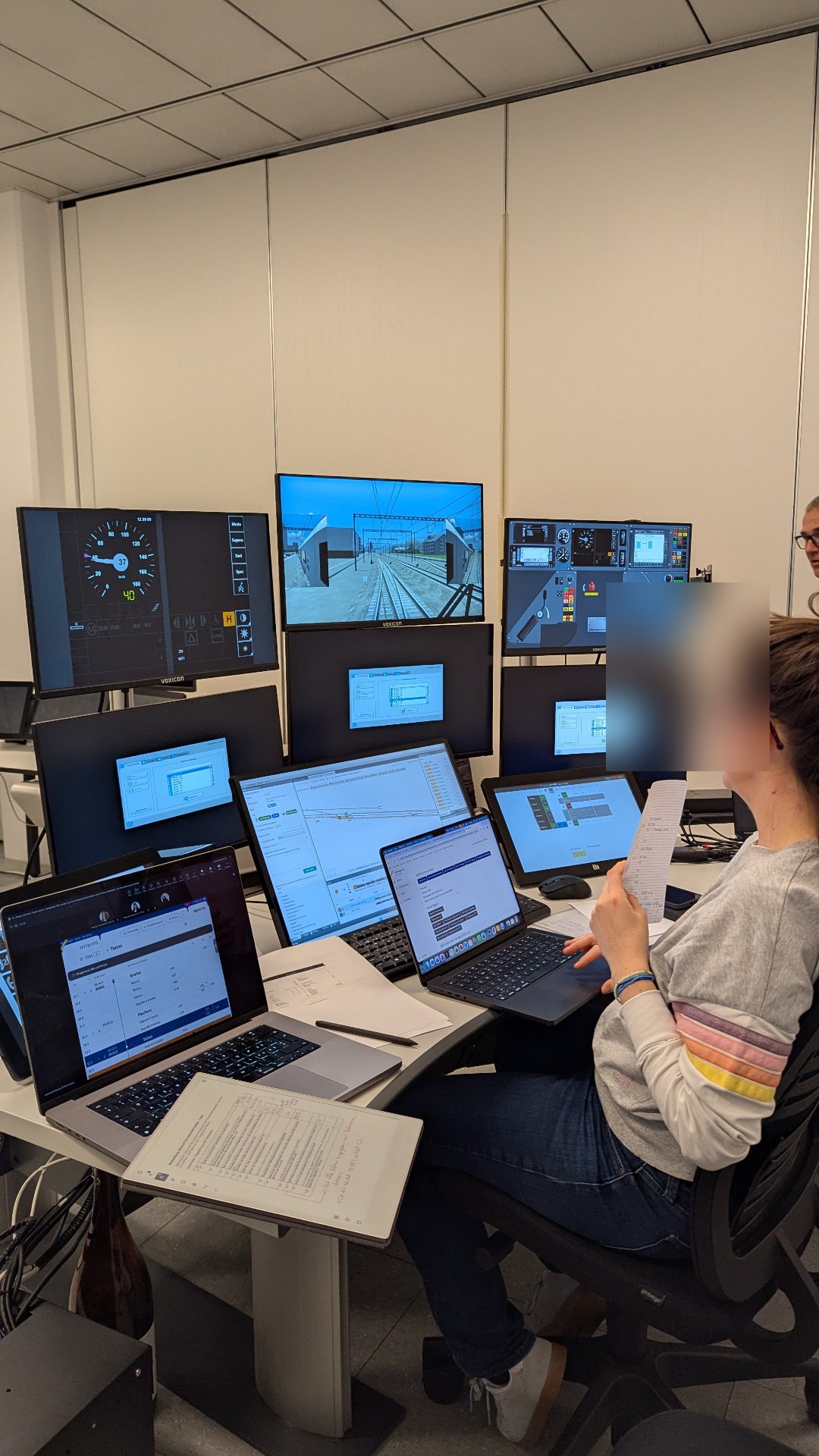 Researcher facing a multi-screen test setup with the DAS iPad, cockpit mirrors and analysis laptops.